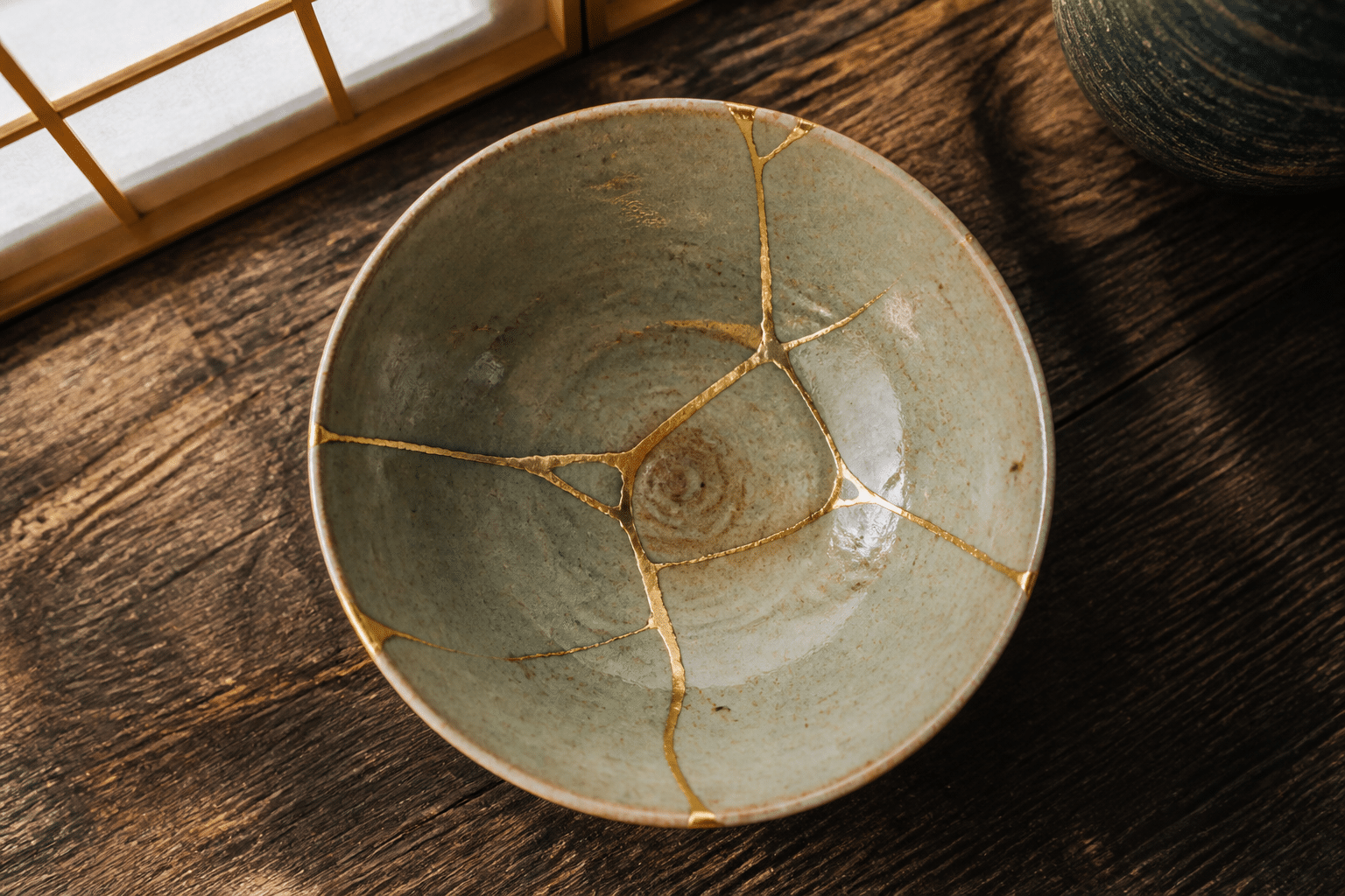 Bol japonais réparé au kintsugi avec des lignes d or sur fond de bois sombre